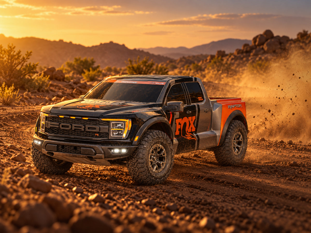 Traxxas Ford Raptor R 4X4 Ultimate kicking up dust on a desert trail at sunset